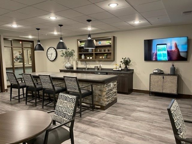 A large room with tables and chairs and a flat screen tv on the wall.