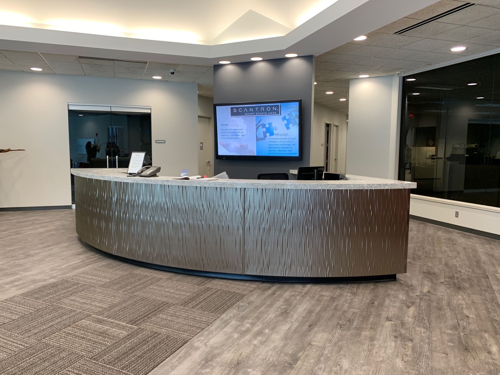 A reception area with a curved counter and a flat screen tv on the wall.