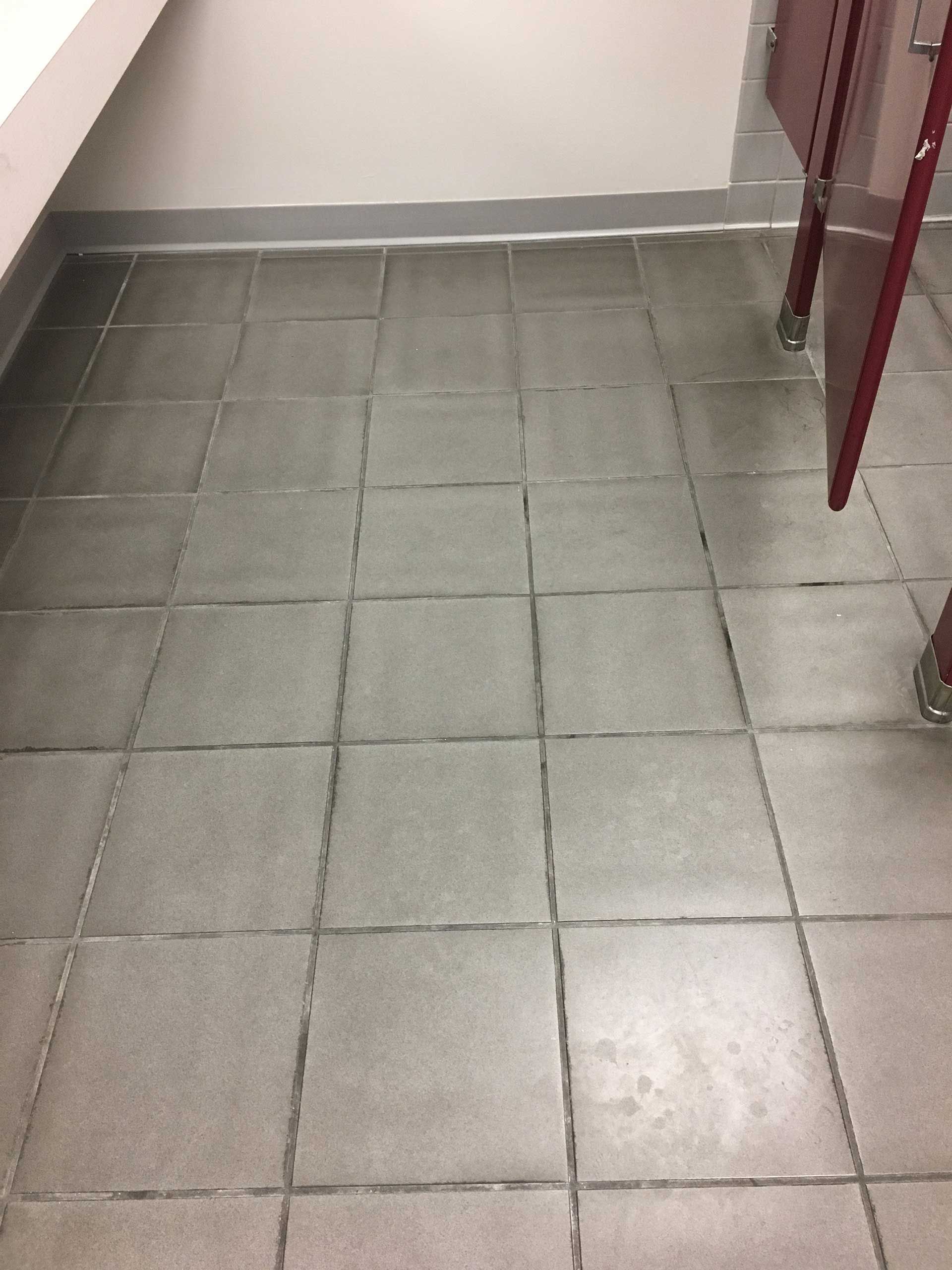 A bathroom with a tiled floor and a red door