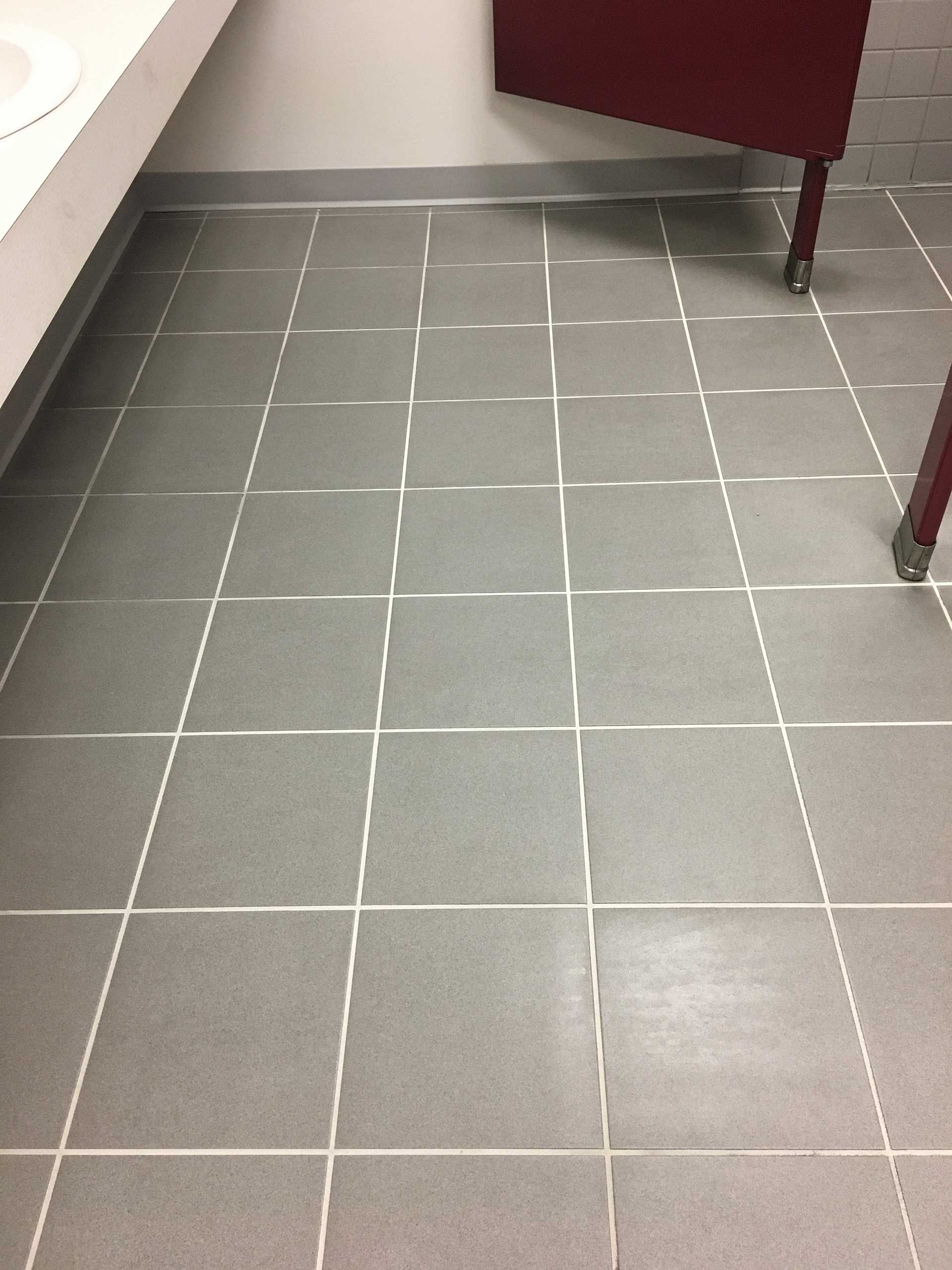 A bathroom floor with gray tiles and white lines