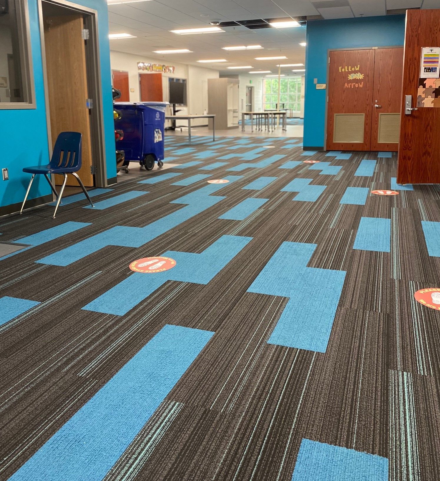 A hallway with blue and black carpet and a blue trash can