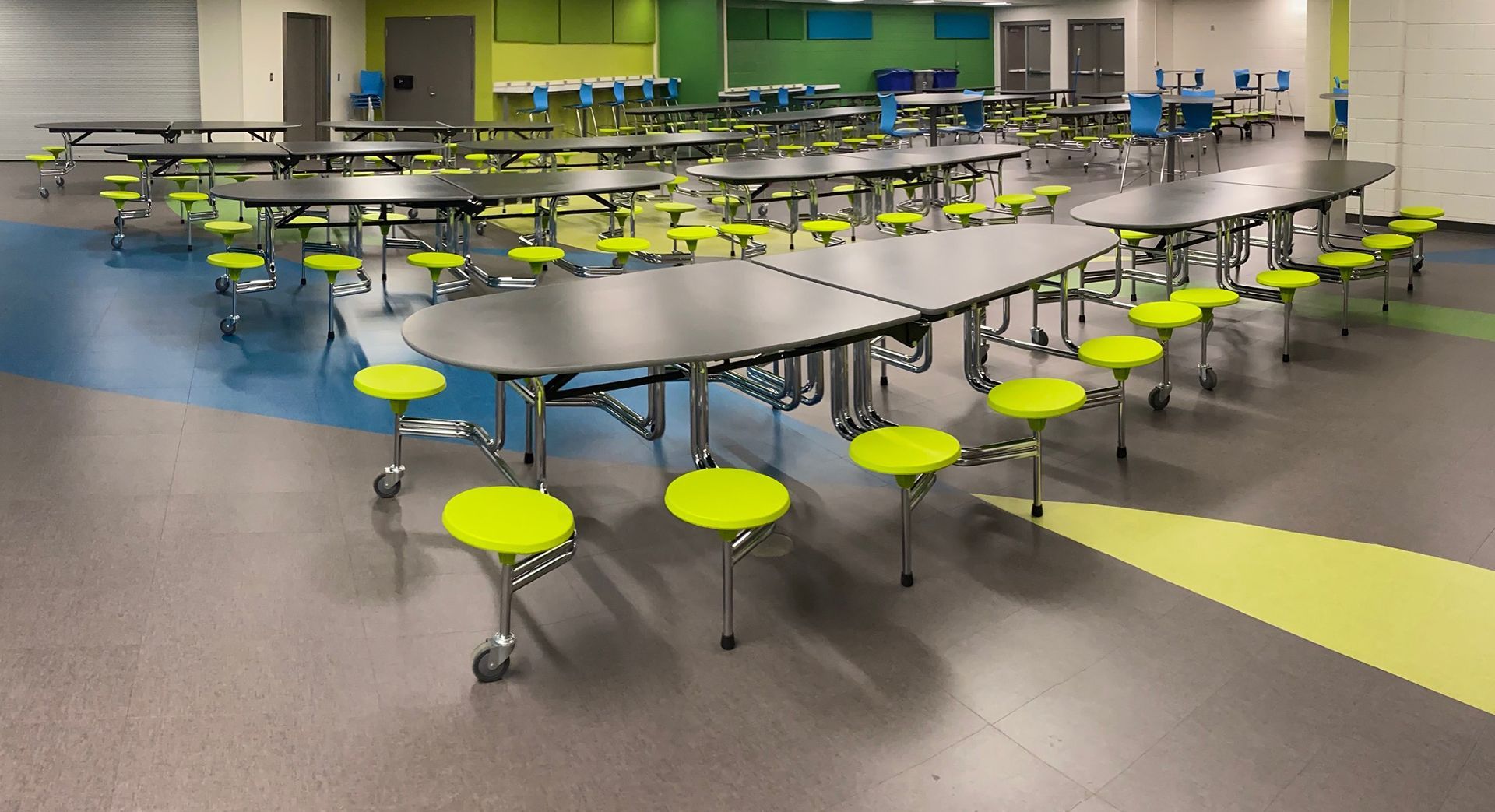 A large room with tables and chairs in a school cafeteria.