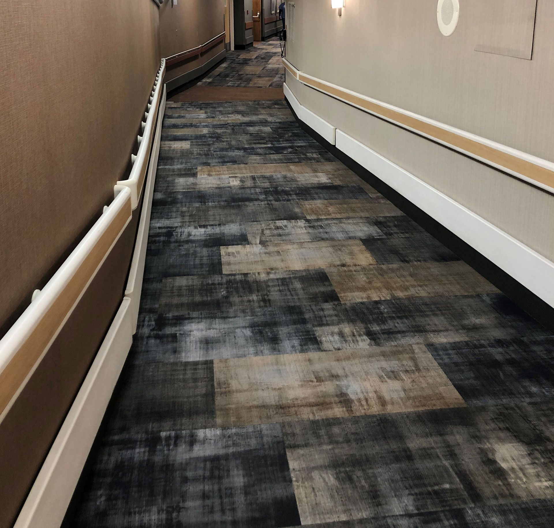 A long hallway with a carpeted floor and a white railing