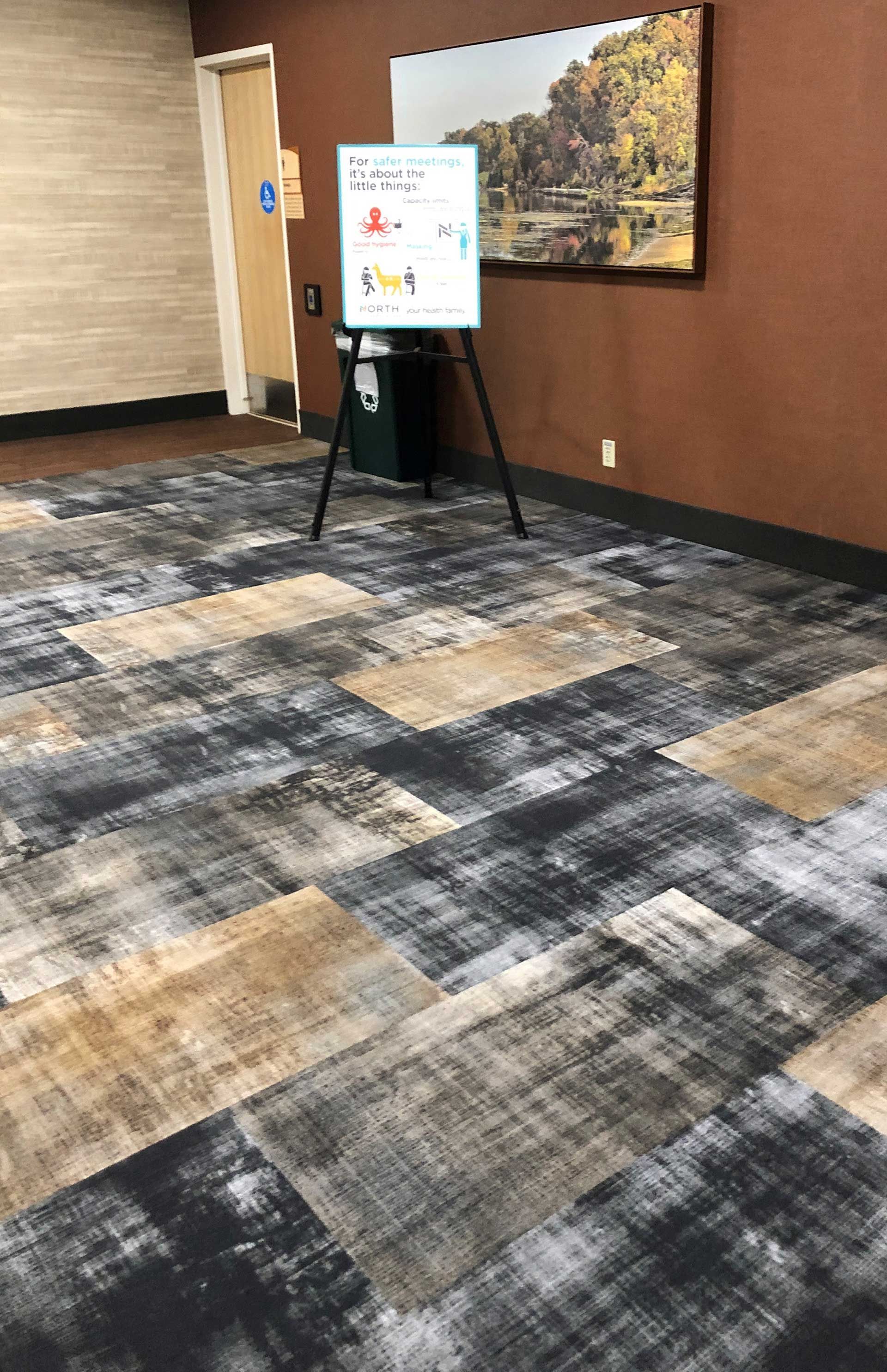 A room with a carpeted floor and a painting on the wall.