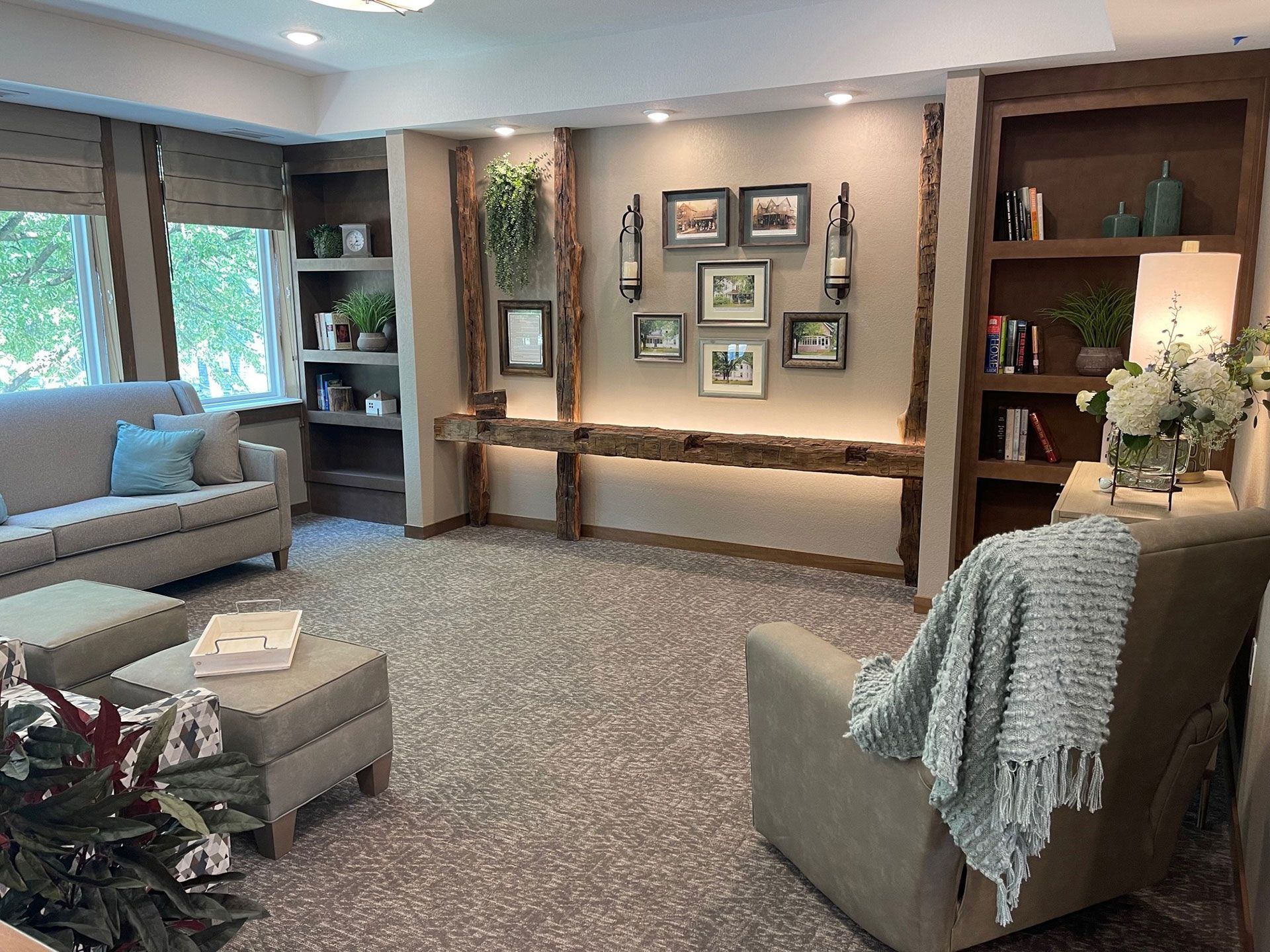 A living room with a couch , chair , ottoman and shelves.