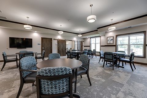 A large room with tables and chairs and a flat screen tv.