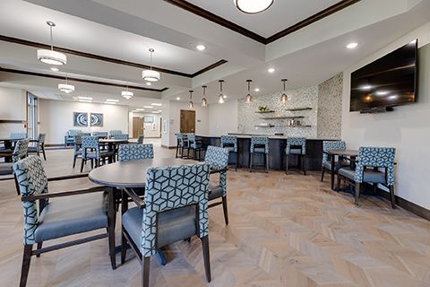 A large room with tables and chairs and a flat screen tv.