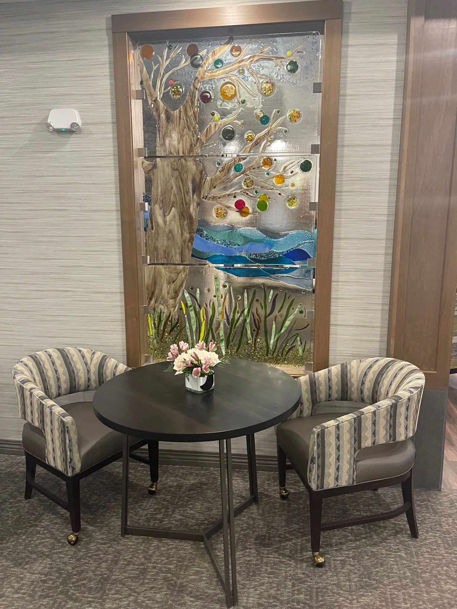There is a table and chairs in front of a stained glass window.