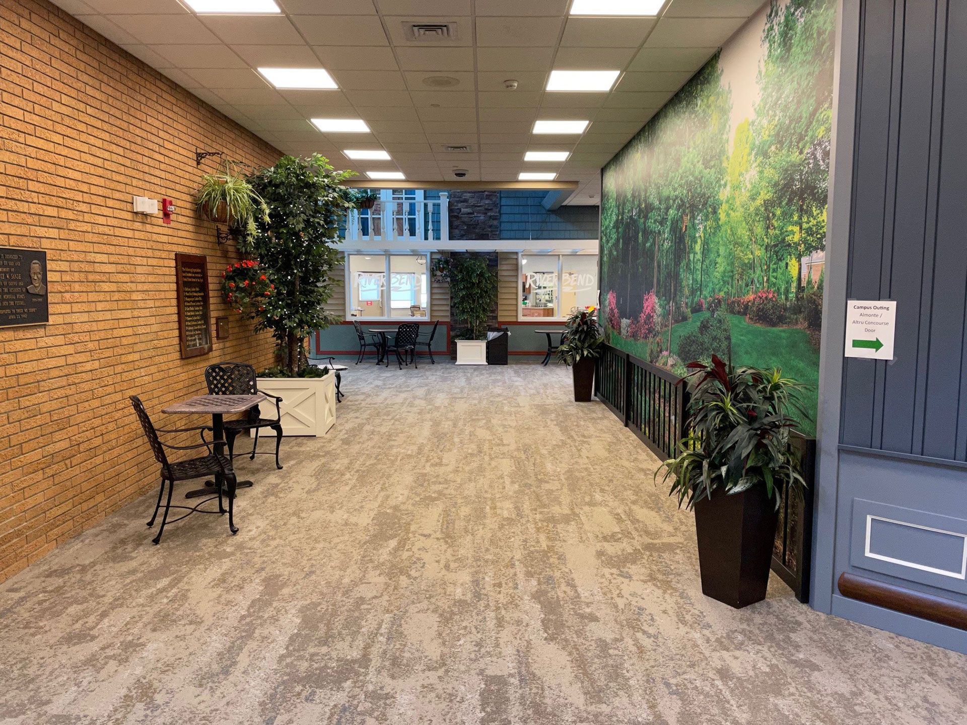 A long hallway with tables and chairs and a picture on the wall.