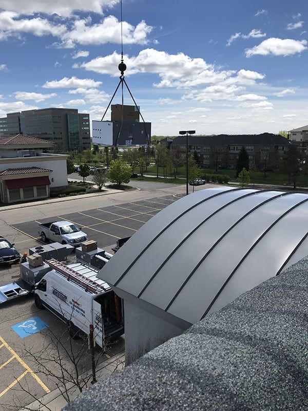 A large building is being lifted by a crane in a parking lot