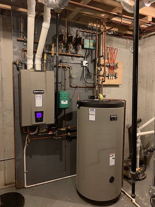 A water heater is sitting in a basement next to a boiler