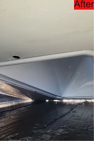 Underside of a white vehicle. Metal components reflect the surface below. Water droplets are visible on the floor.