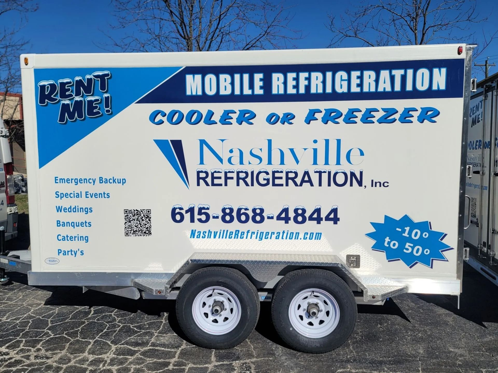White mobile refrigeration trailer with blue text: 