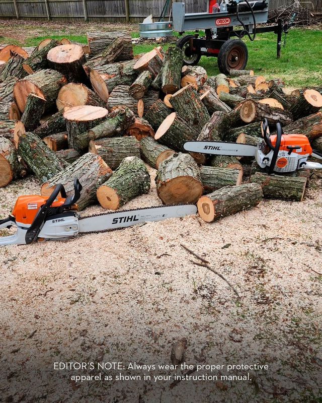 Pile of logs with two chainsaws and a wood splitter outdoors.