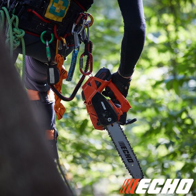 Person in harness using orange ECHO chainsaw to cut tree branch.