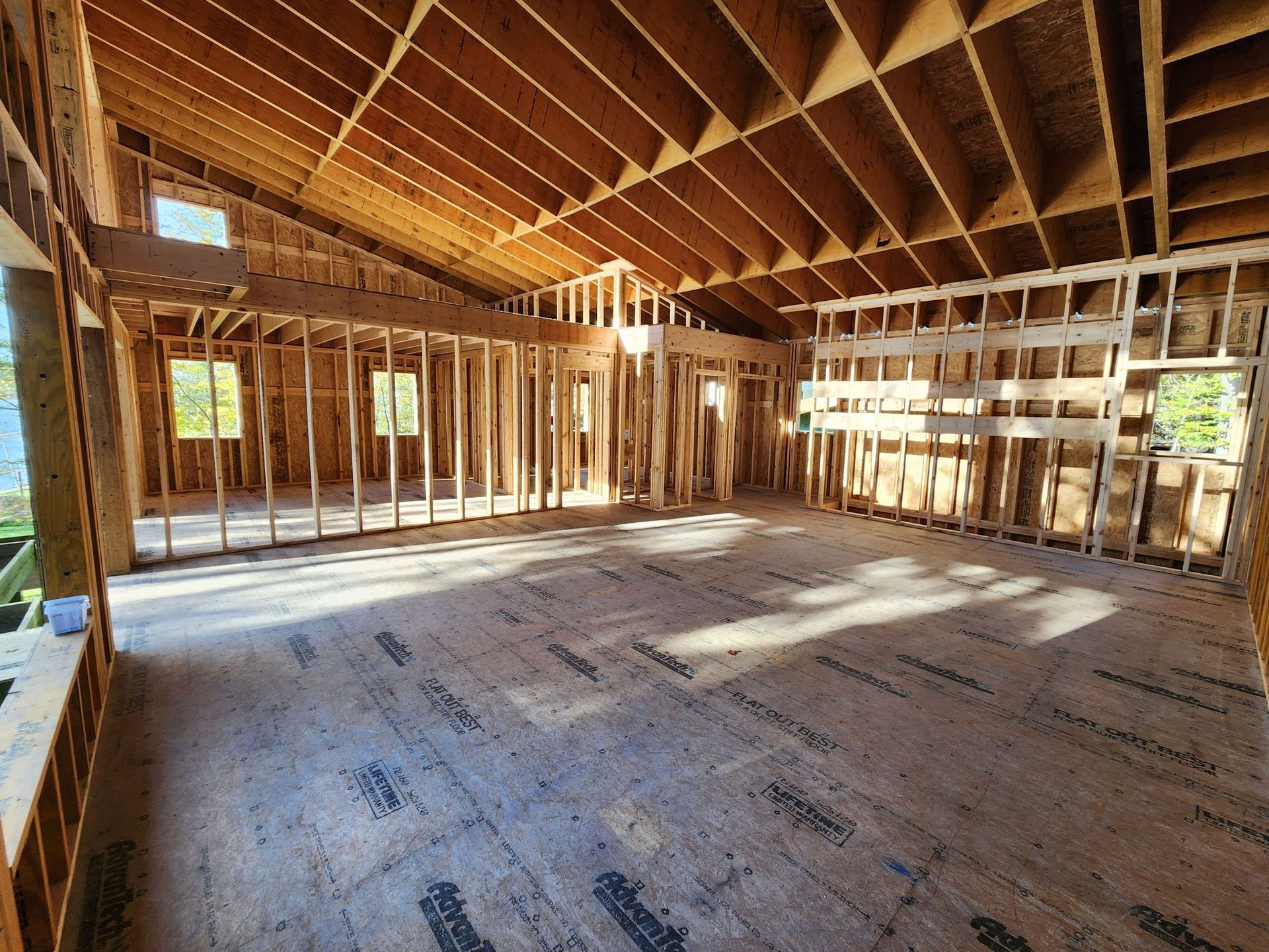 Interior of a building under construction, wooden framework, open layout, natural light, unfinished flooring.
