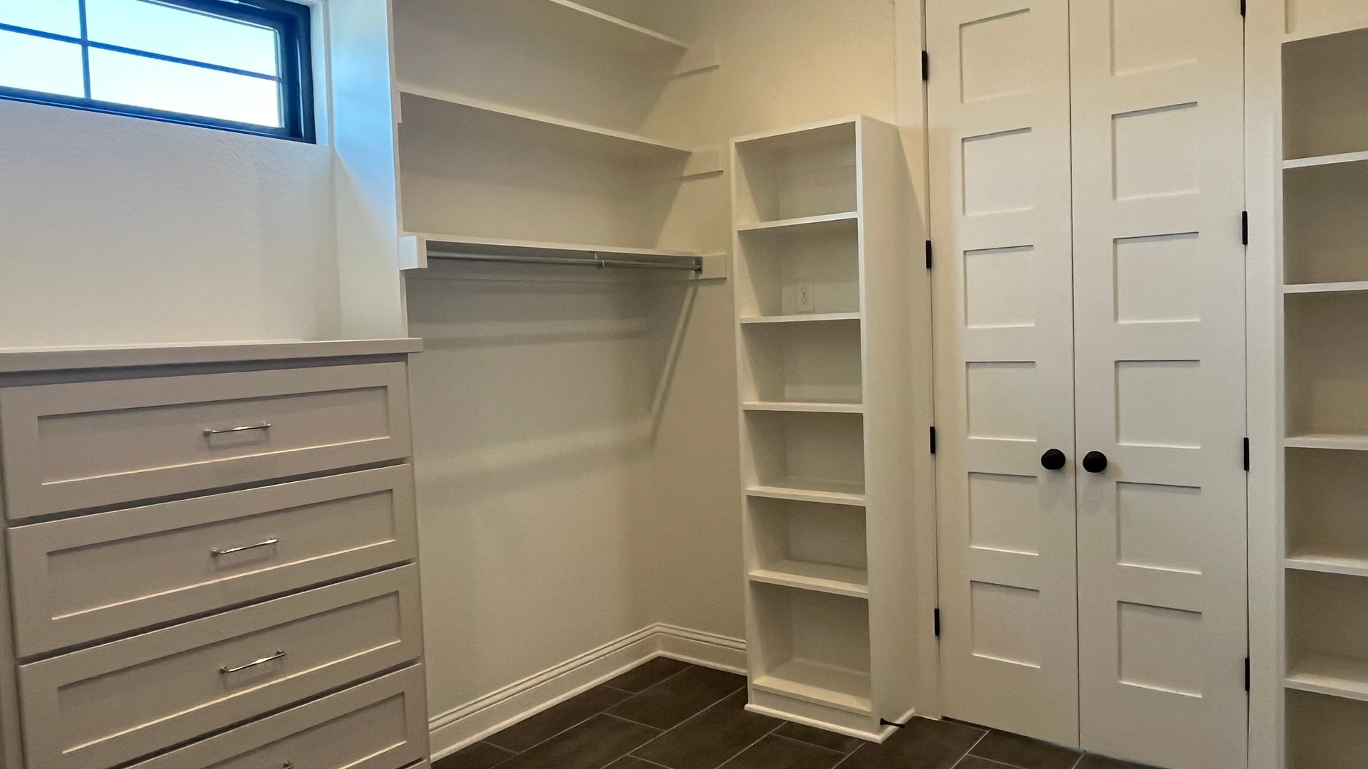 A walk in closet with lots of shelves and drawers
