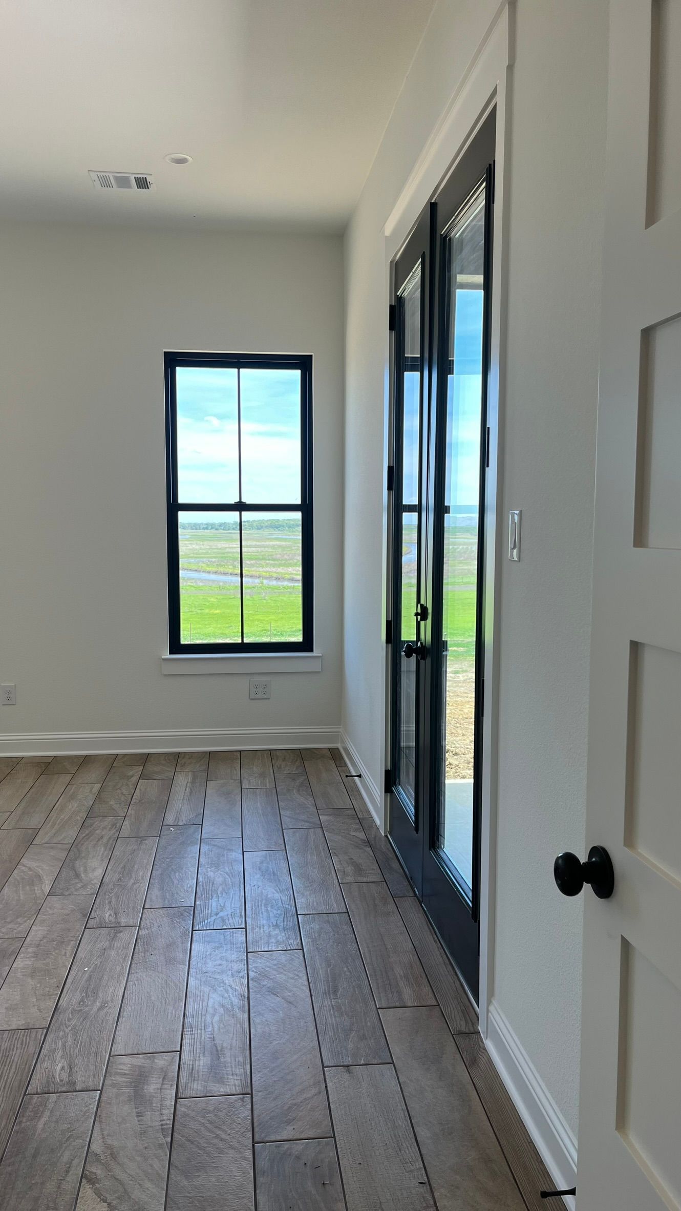 An empty master bedroom with a wooden floor and a window