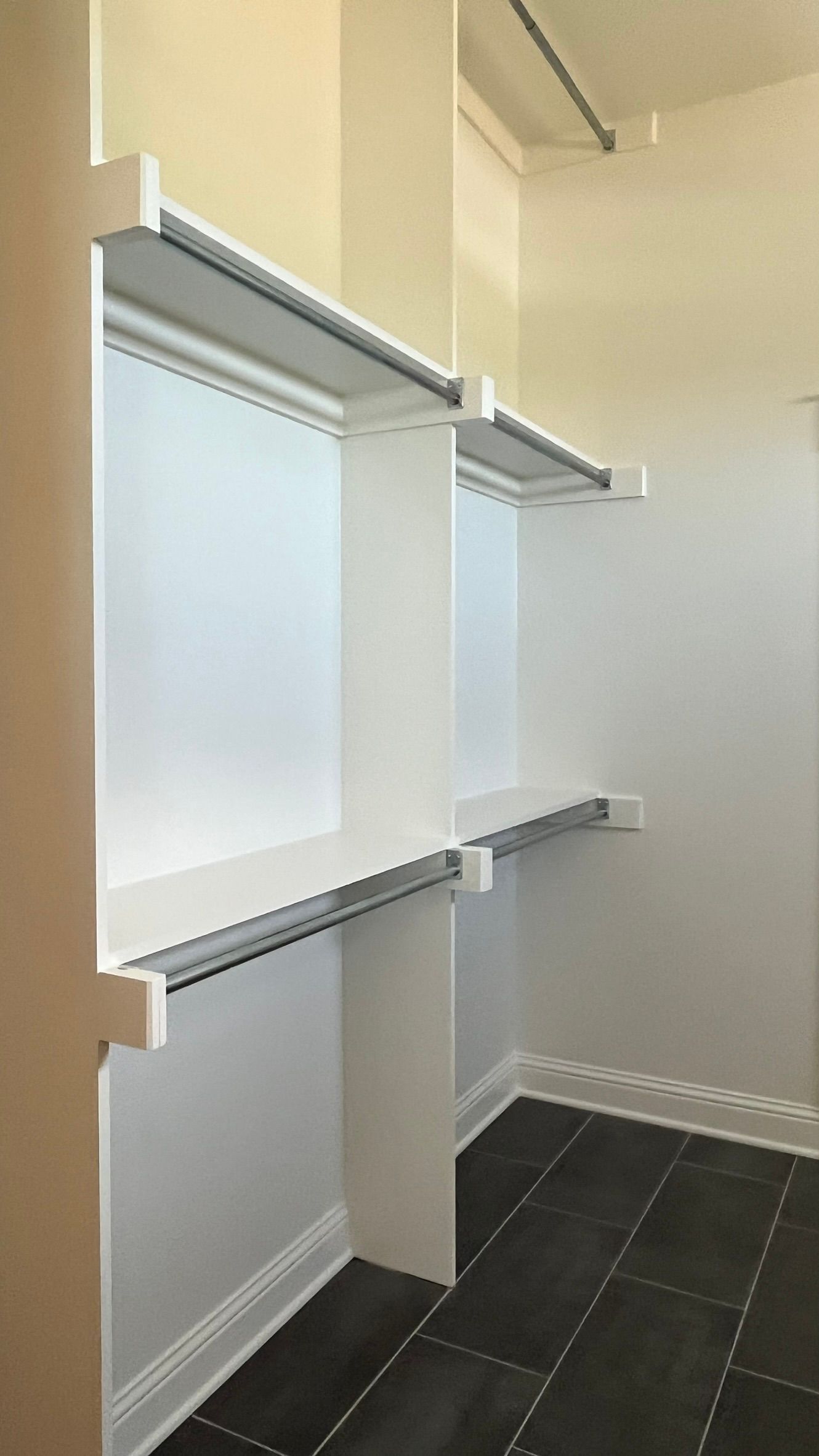 A walk in closet with white shelves and black tile floors