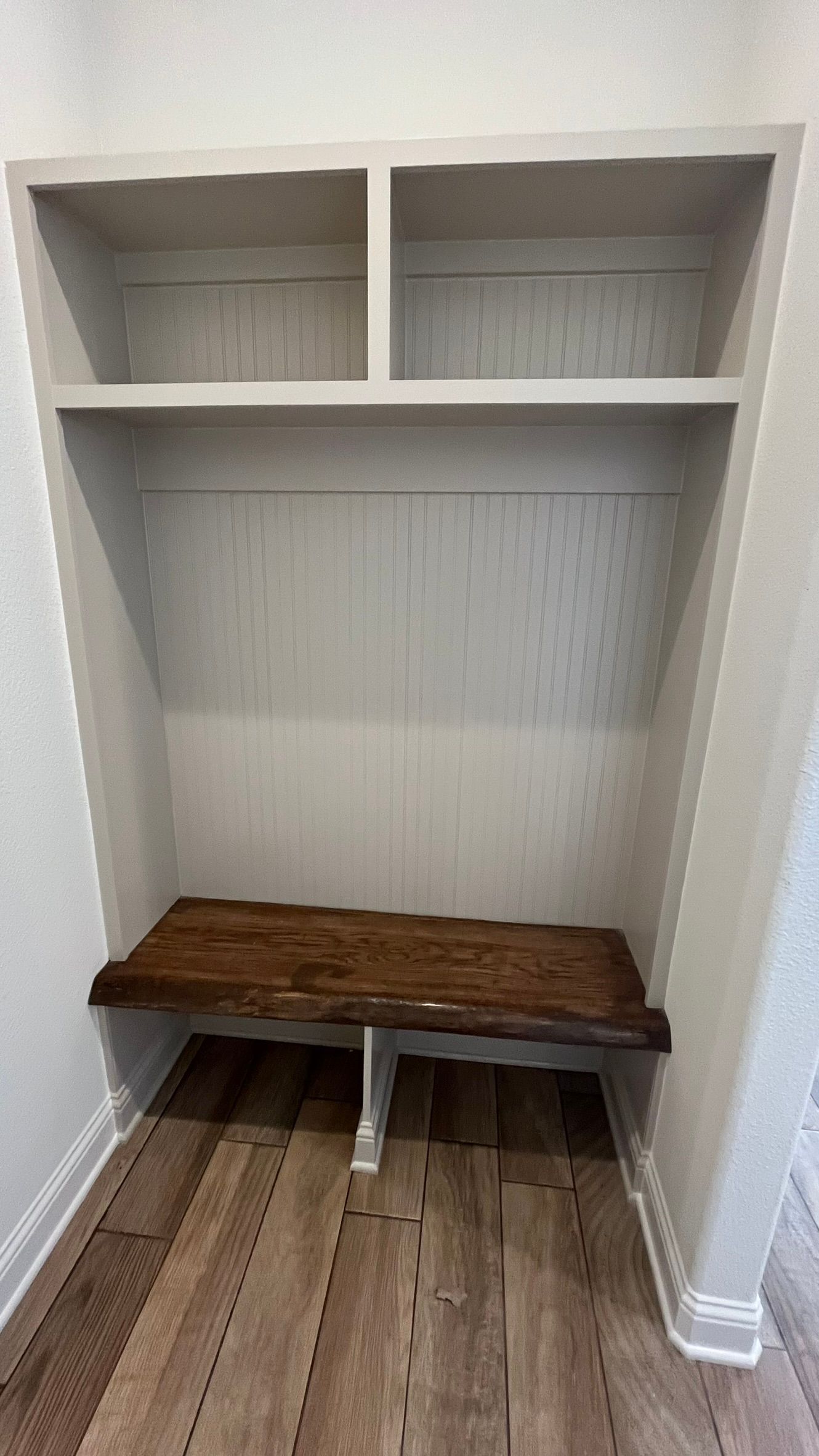 A mud room area with a bench and shelves in it