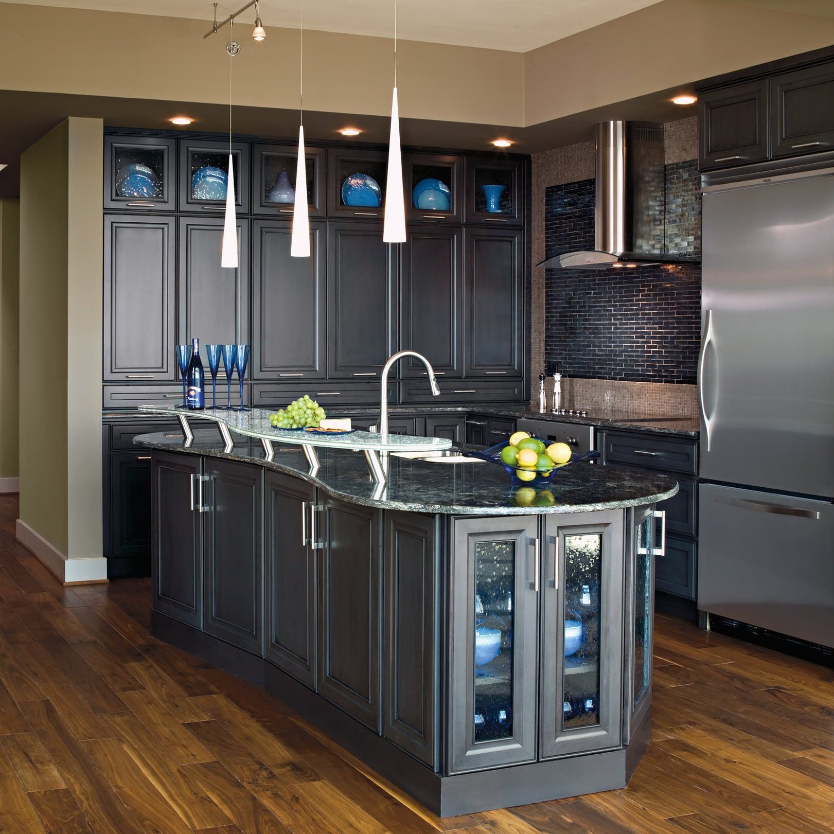 A kitchen with dark gray cabinets and stainless steel appliances