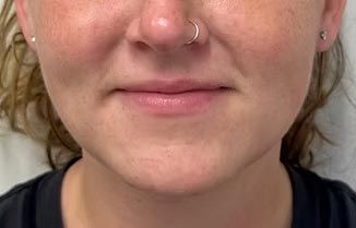 A close up of a woman 's face with a nose ring.