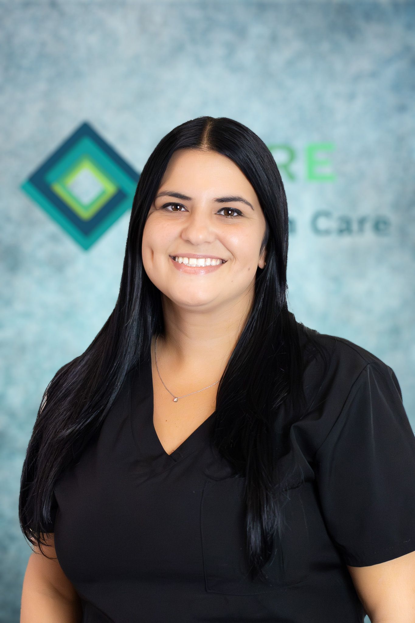 A woman in a black scrub top is smiling for the camera.