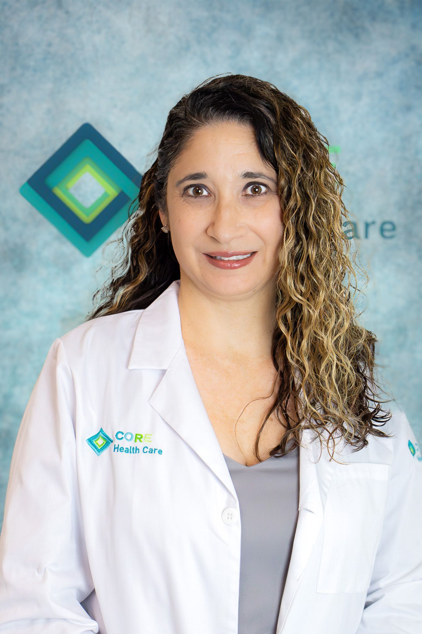 A woman in a white lab coat is smiling for the camera.