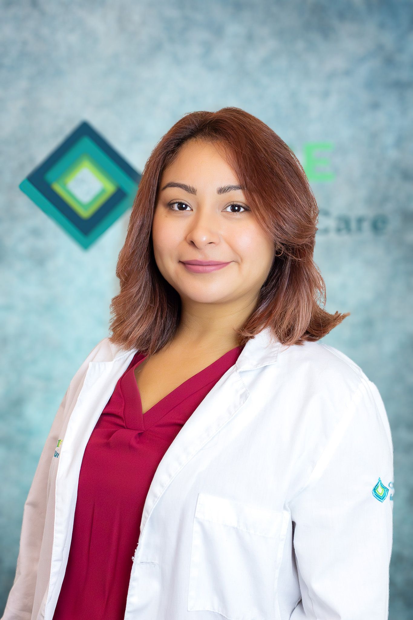 A woman in a white lab coat and red scrub top is posing for a picture.