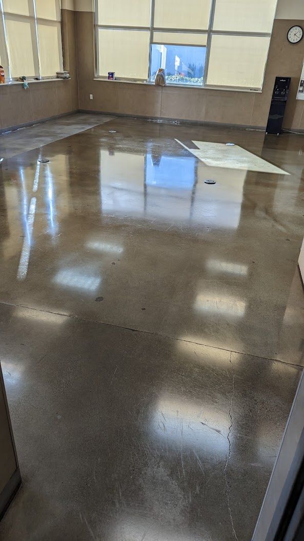 Empty classroom with a glossy flooded floor reflecting ceiling lights and windows.