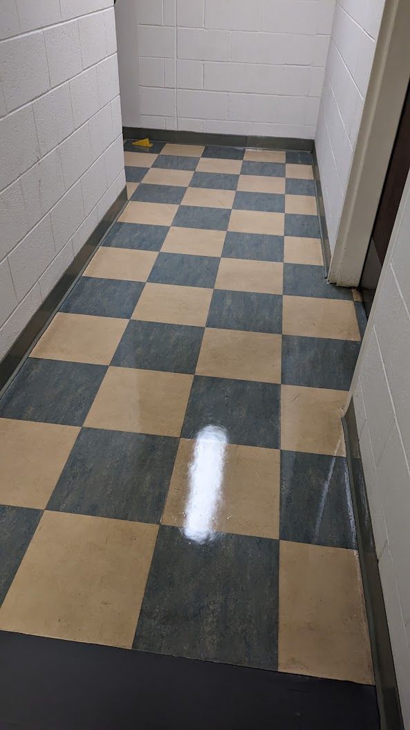 Narrow hallway with blue and tan checkered tile floor and white brick walls.
