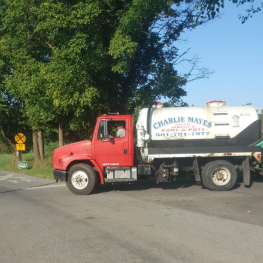 Red septic service truck on a road; white tank with 