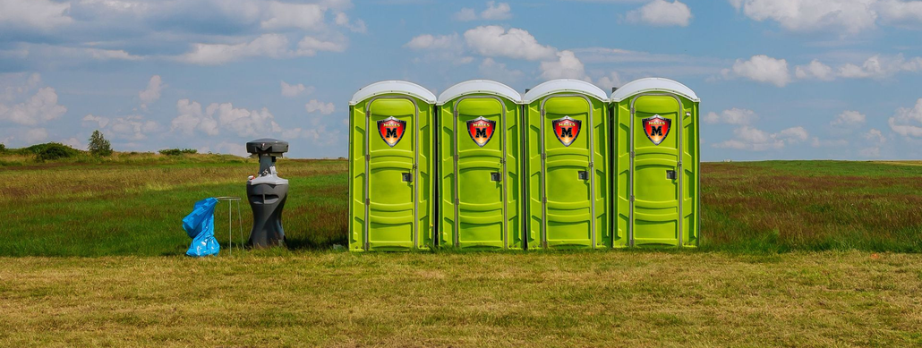 Row of blue portable toilets under a partly cloudy sky.