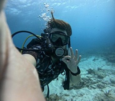 A scuba diver is taking a selfie in the ocean