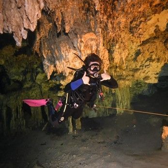 A scuba diver is giving a thumbs up in a cave