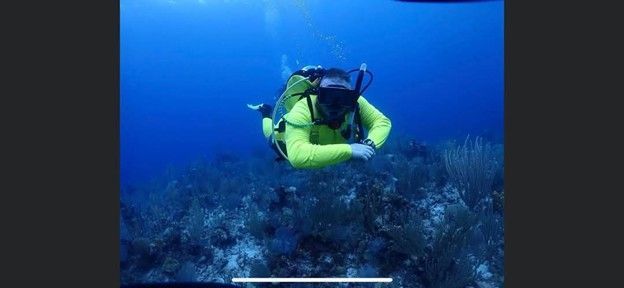 A scuba diver is swimming in the ocean near a coral reef.