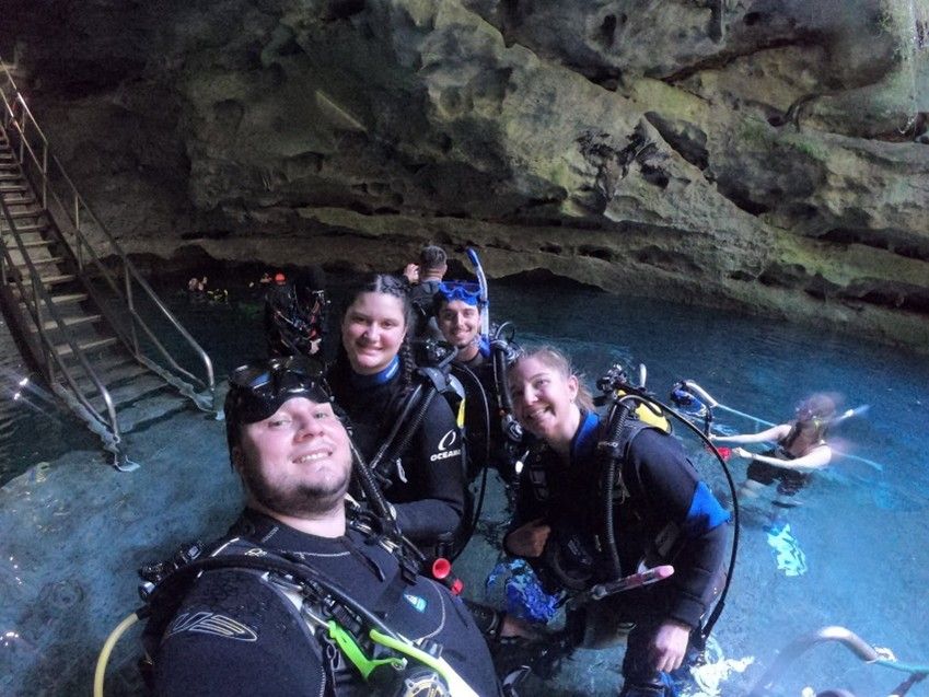 A group of scuba divers are posing for a picture in a cave.