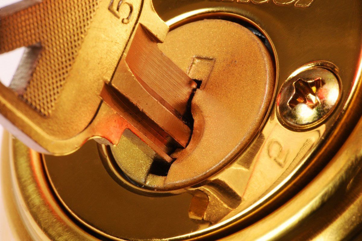 Close-up of a brass lock cylinder with a key inserted and turned