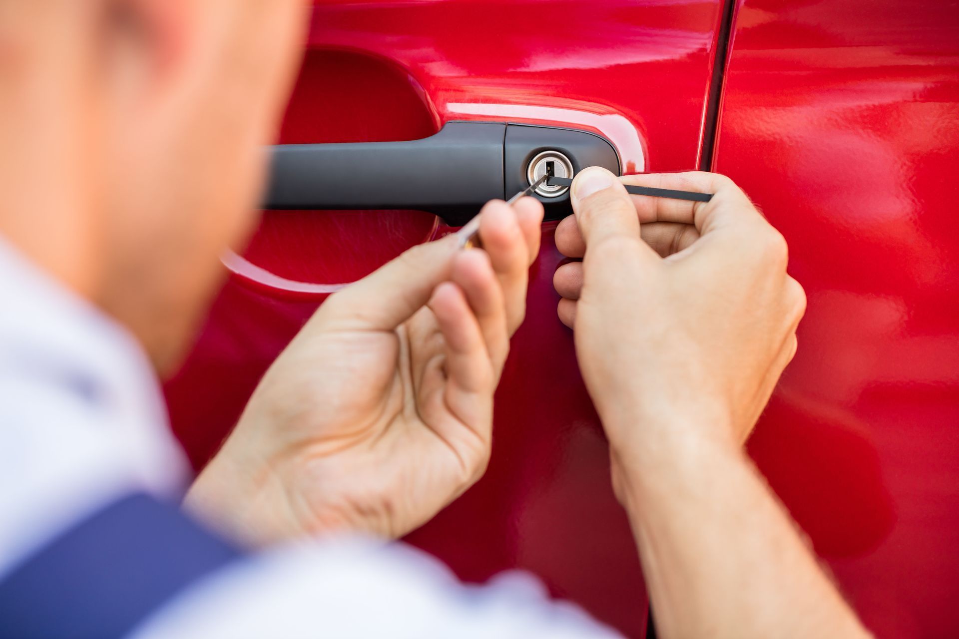 Hands unlocking a red car door with a key in the lock