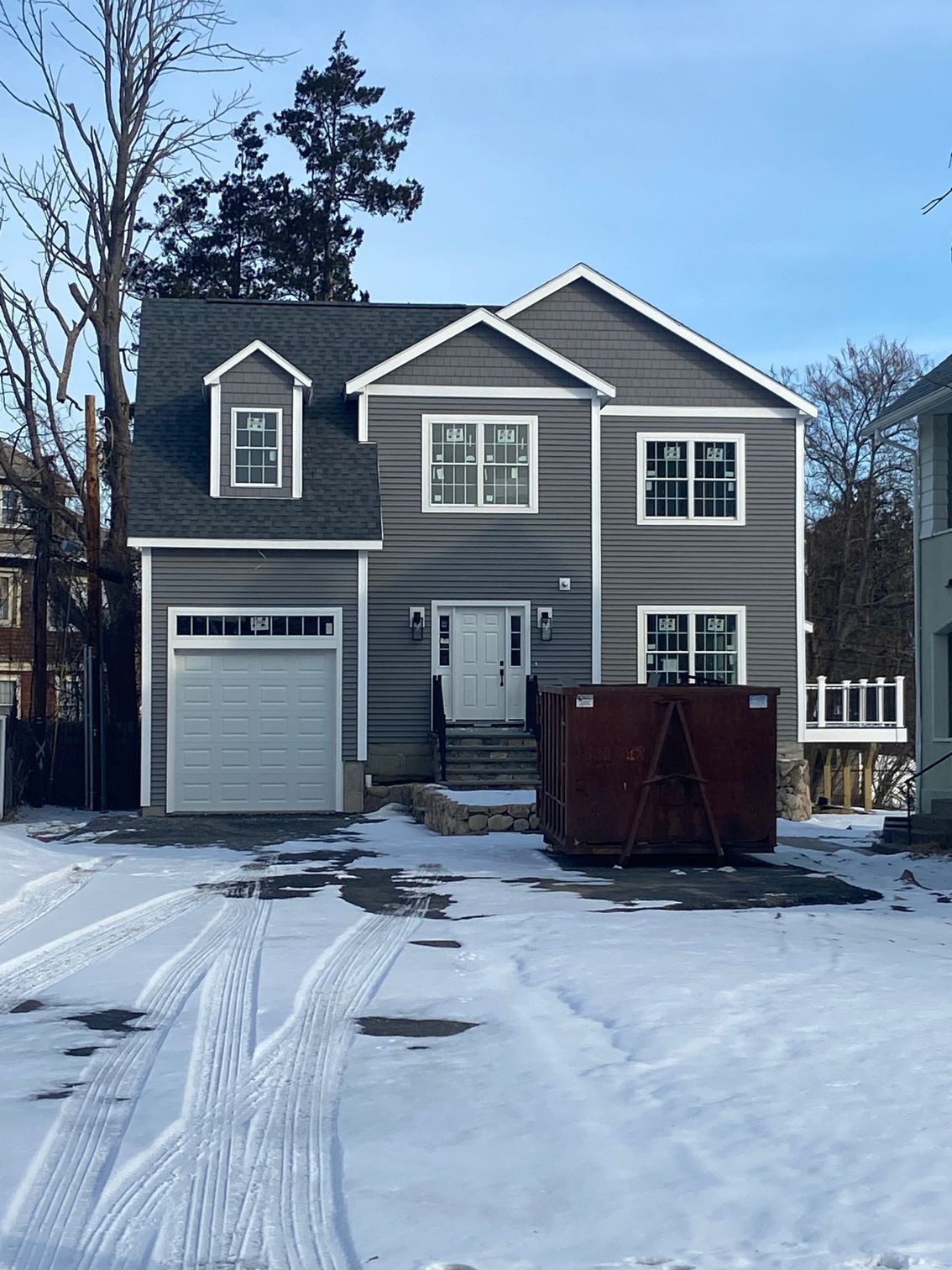 New two-story house with gray siding, white trim, and a garage in a snowy setting.