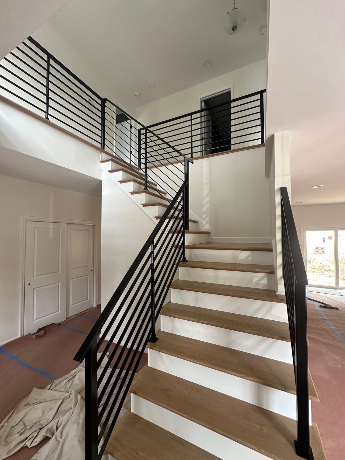 Staircase with wooden steps and black metal railings in a modern home.