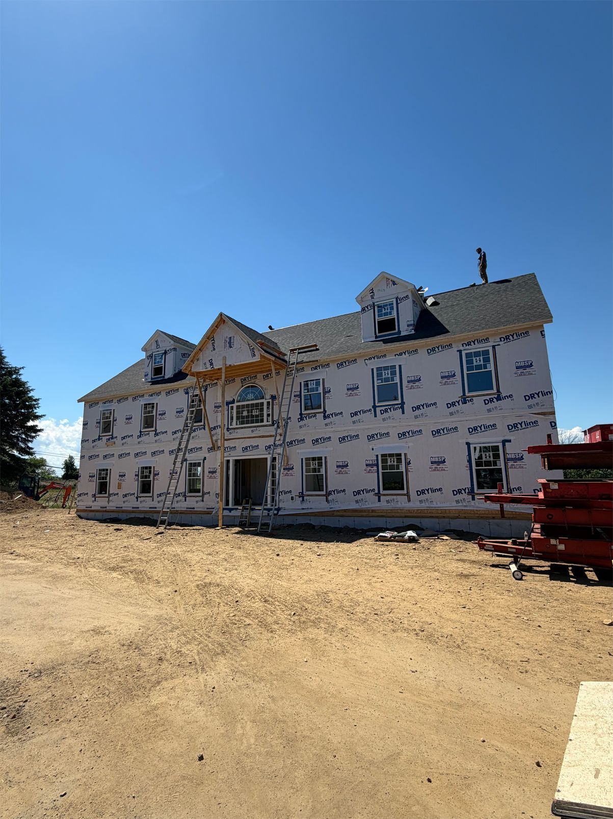 Partially built white house with exposed framing under a clear blue sky