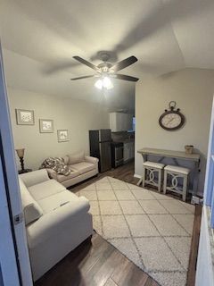 A living room with a couch, table, stools and a ceiling fan