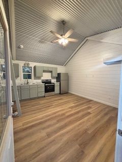 A kitchen with a refrigerator, stove, sink and ceiling fan`