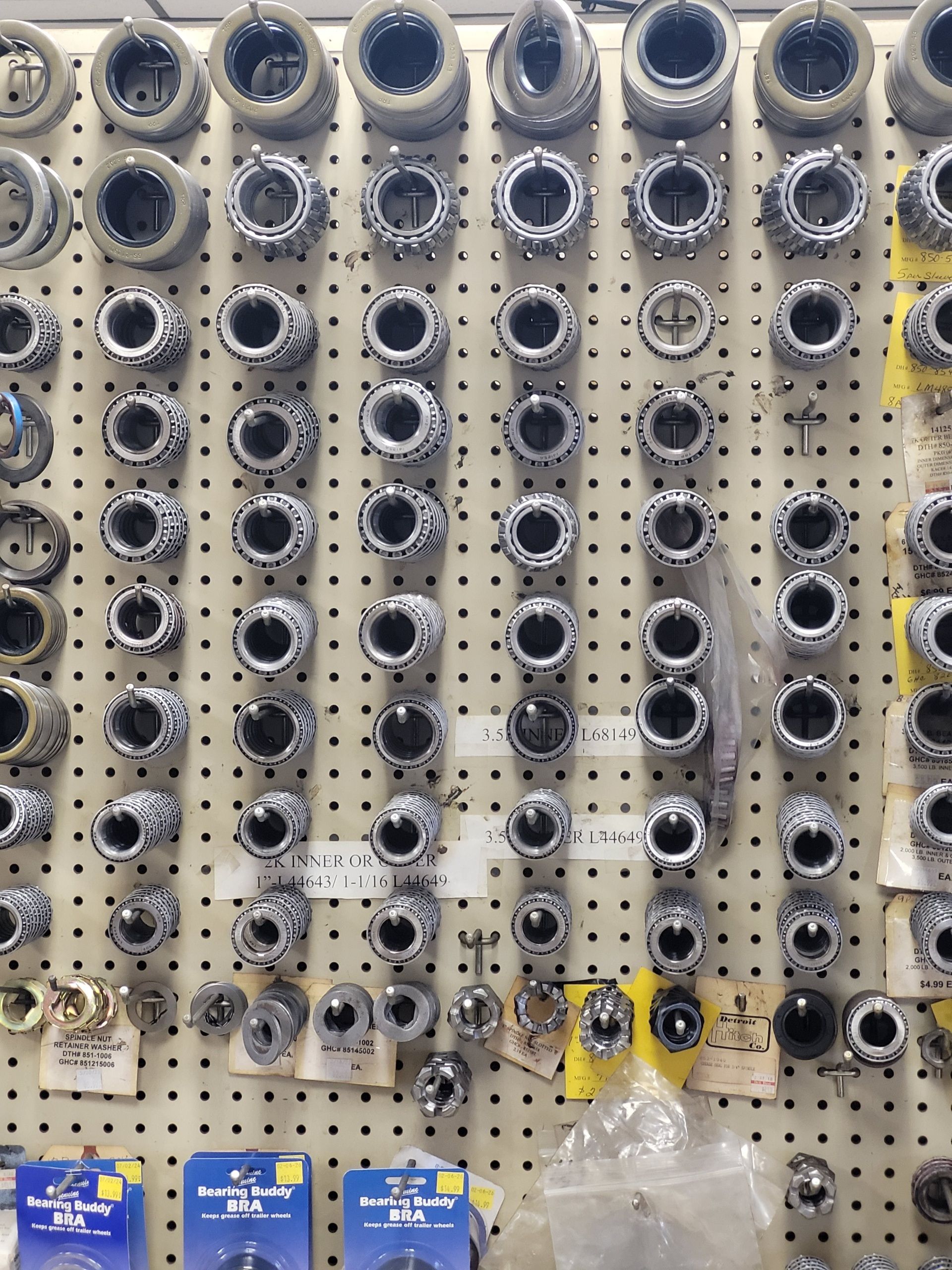 A pegboard display in a retail store filled with various metal mechanical bearing or bushing components.
