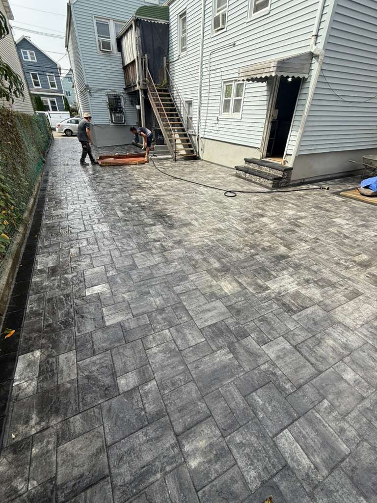 Newly paved alley with workers; buildings in background. Gray paving stones.