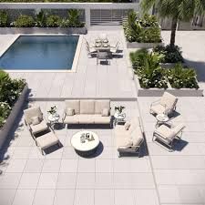 Patio with pool, seating areas, dining table, and greenery on a sunny day.