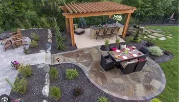 Outdoor patio with stone floor, pergola, bar, and dining area.