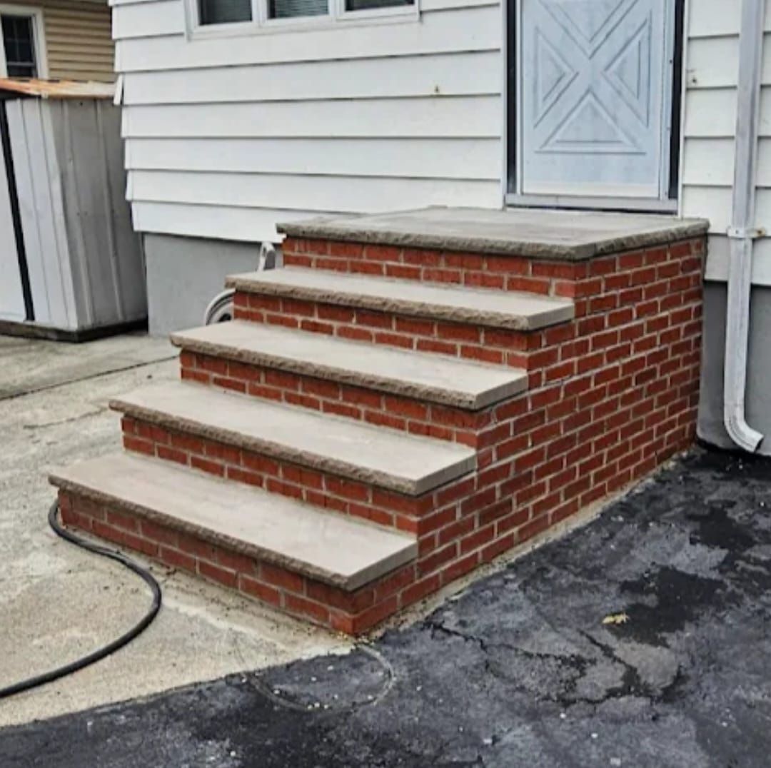 Brick steps leading to a white door, set against a white siding house.