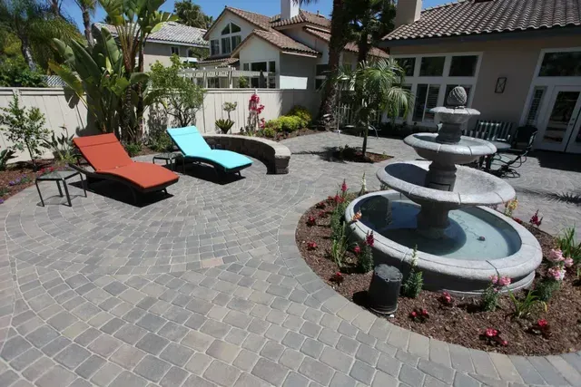 Patio with stone pavers, lounge chairs, fountain, and plants.